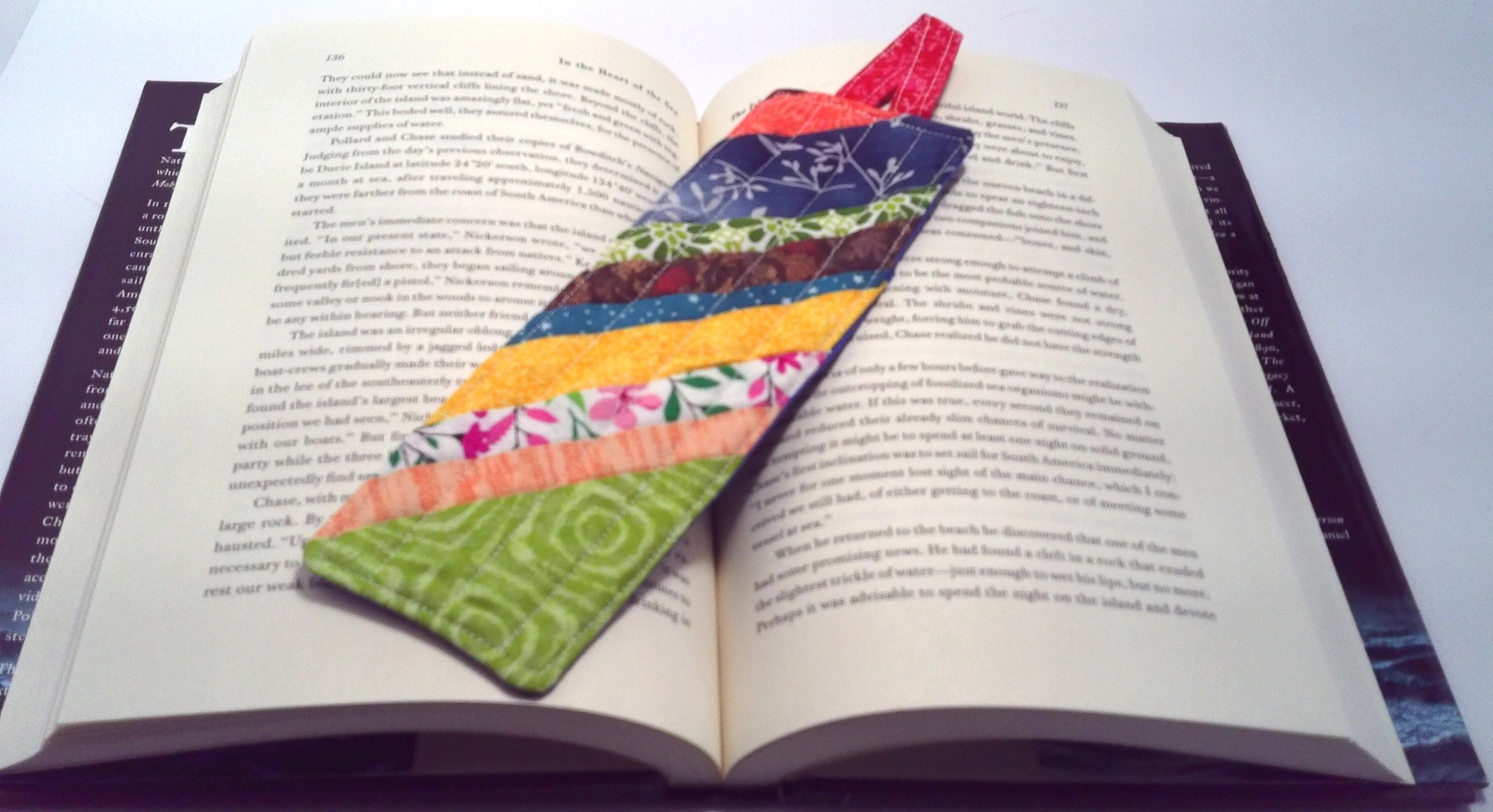 Handmade fabric bookmark resting on an open book — best-value quilted gifts for book lovers