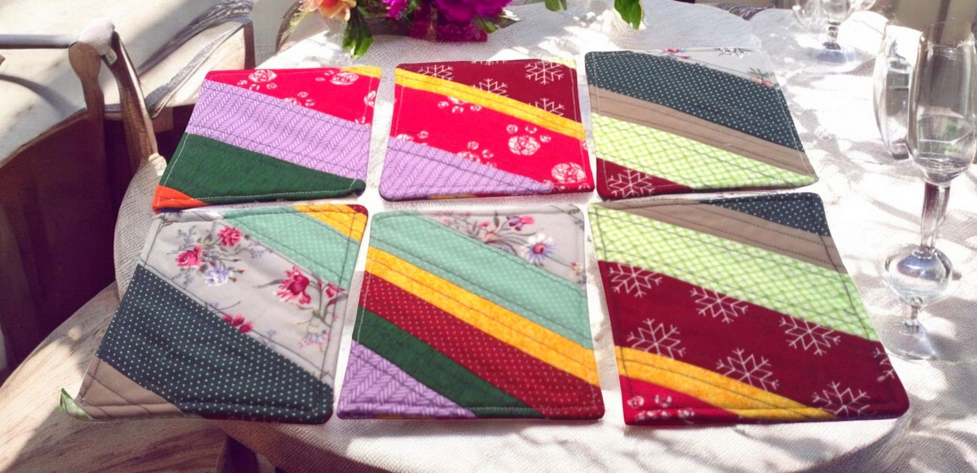 Colorful quilted coasters on white tablecloth